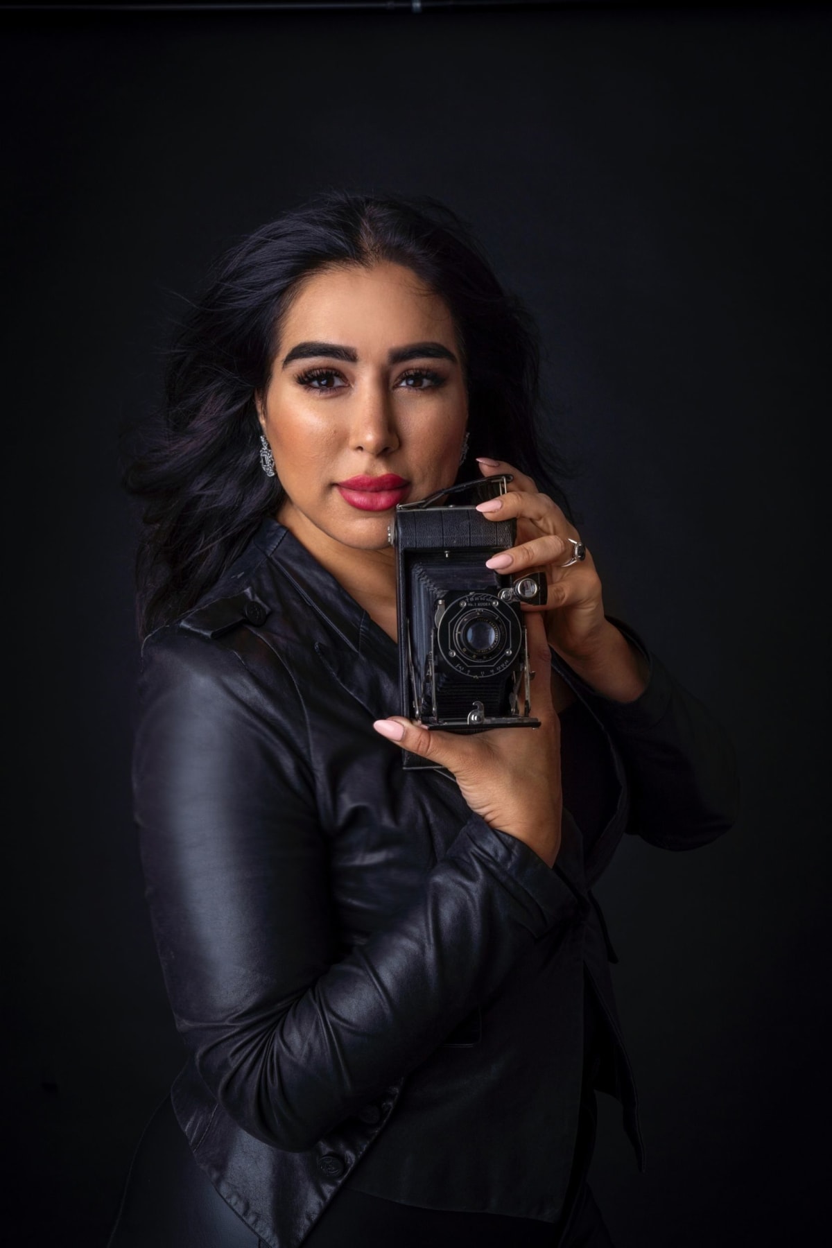 Dana Sefati — Montreal portrait photographer holding vintage camera in professional studio setting